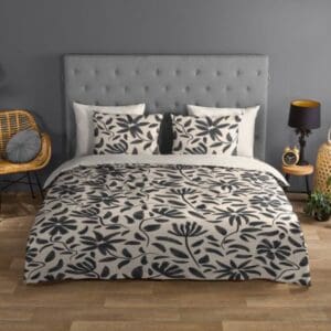 Slaapkamer met grijs bed en bladmotief dekbedovertrek.