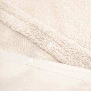 Zachte, crèmekleurige fleece stof met drukknopen.