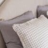 Zachte kussens met ruitjesmotief op bed.