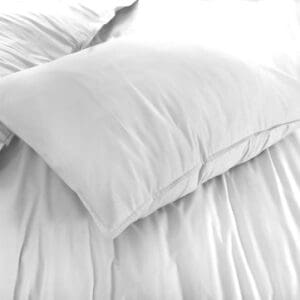 Wit kussen op een net opgemaakt bed.