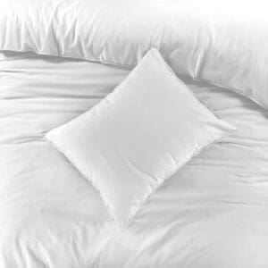 Wit kussen op bed met dekbedovertrek