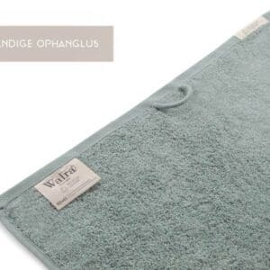 Groene handdoek met ophanglus en label Walra.